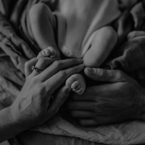 Newborn baby feet held by parents, reflecting family bonding with The Birth Teacher in Australia