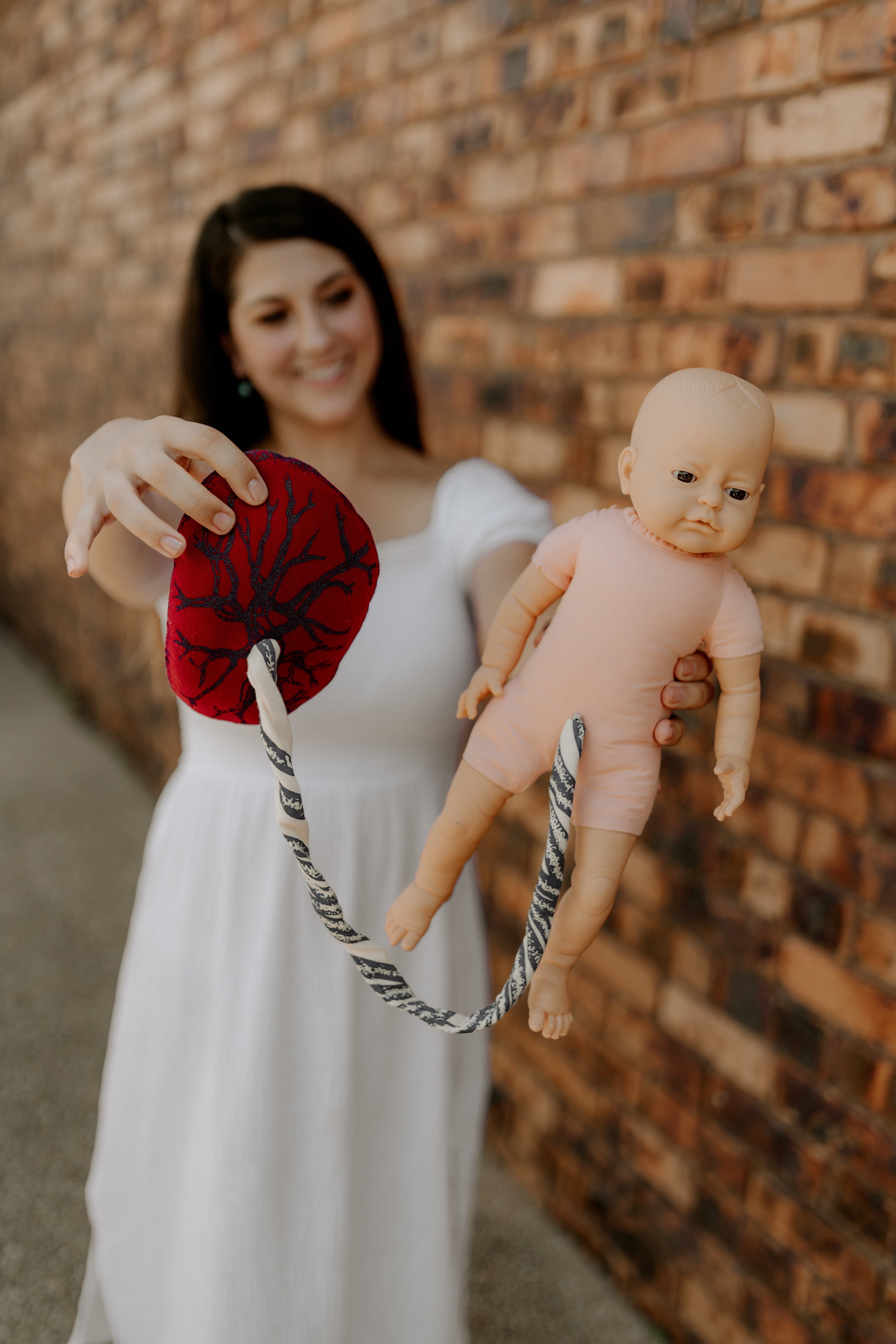 "The Birth Teacher holding a birth education doll with a placenta, used to demonstrate the stages of childbirth in Emerald QLD"