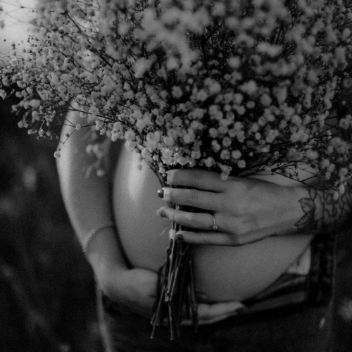 Pregnant Person holding a bouquet of flowers with a blurred background