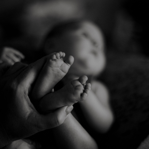 Close-up of a baby's feet being held by an adult hand, with a blurred background