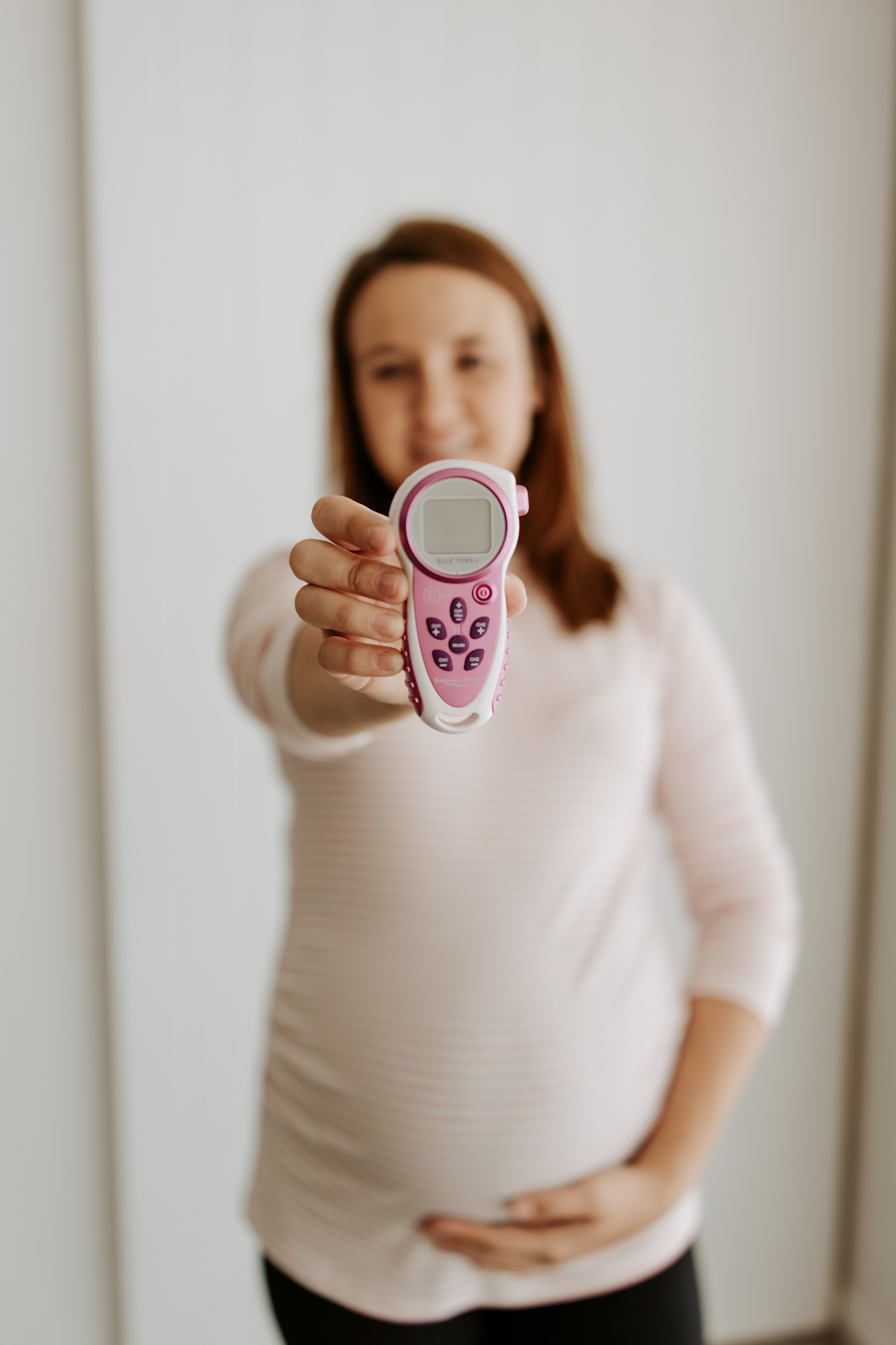 Pregnant Woman holding a TENS machine available for hire from The Birth Teacher in Emerald QLD, Australia